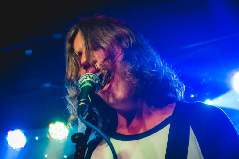 a man with a microphone and a concert scene in the background