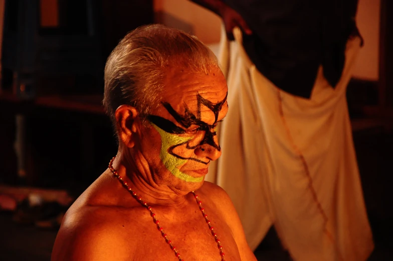 a man with his face painted in orange and yellow