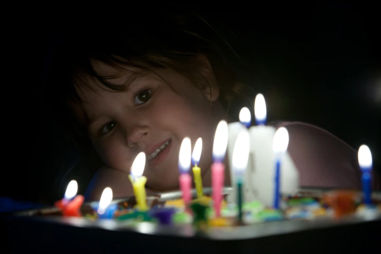 a child looking at candles with his hand on a tray