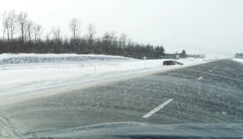 a couple of vehicles are driving down a highway in the winter