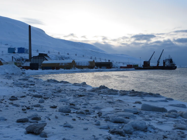 a dock with snow and ice chunks and a boat docked in the water