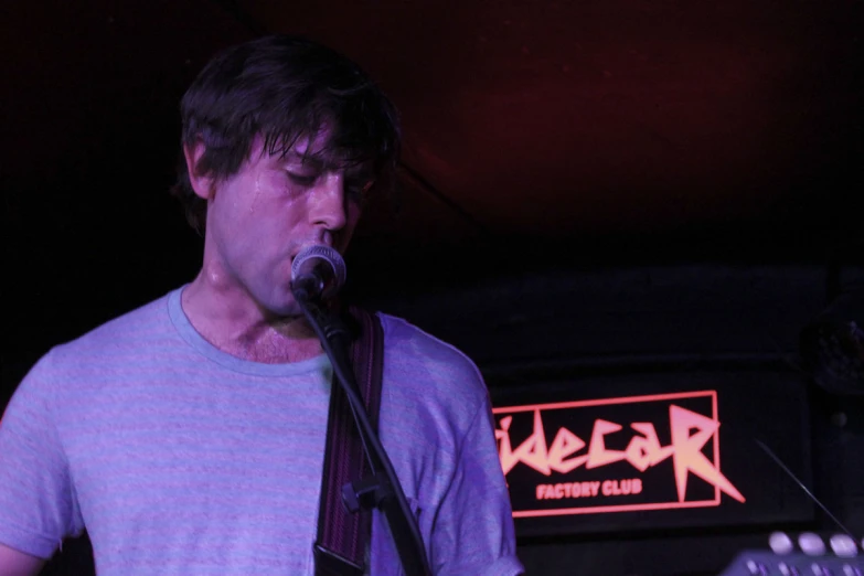 the man is singing into a microphone in front of a guitar