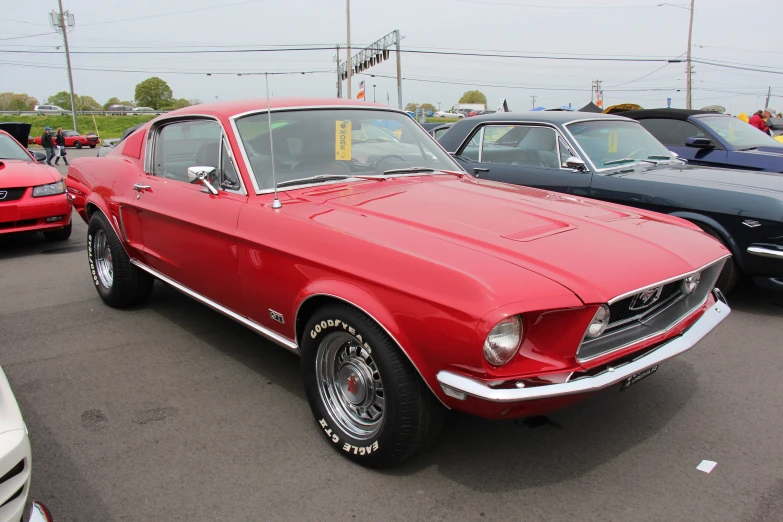 an old red mustang sits in a parking lot