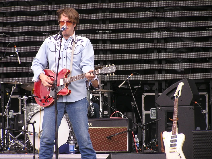 the man is singing into his red guitar at the concert