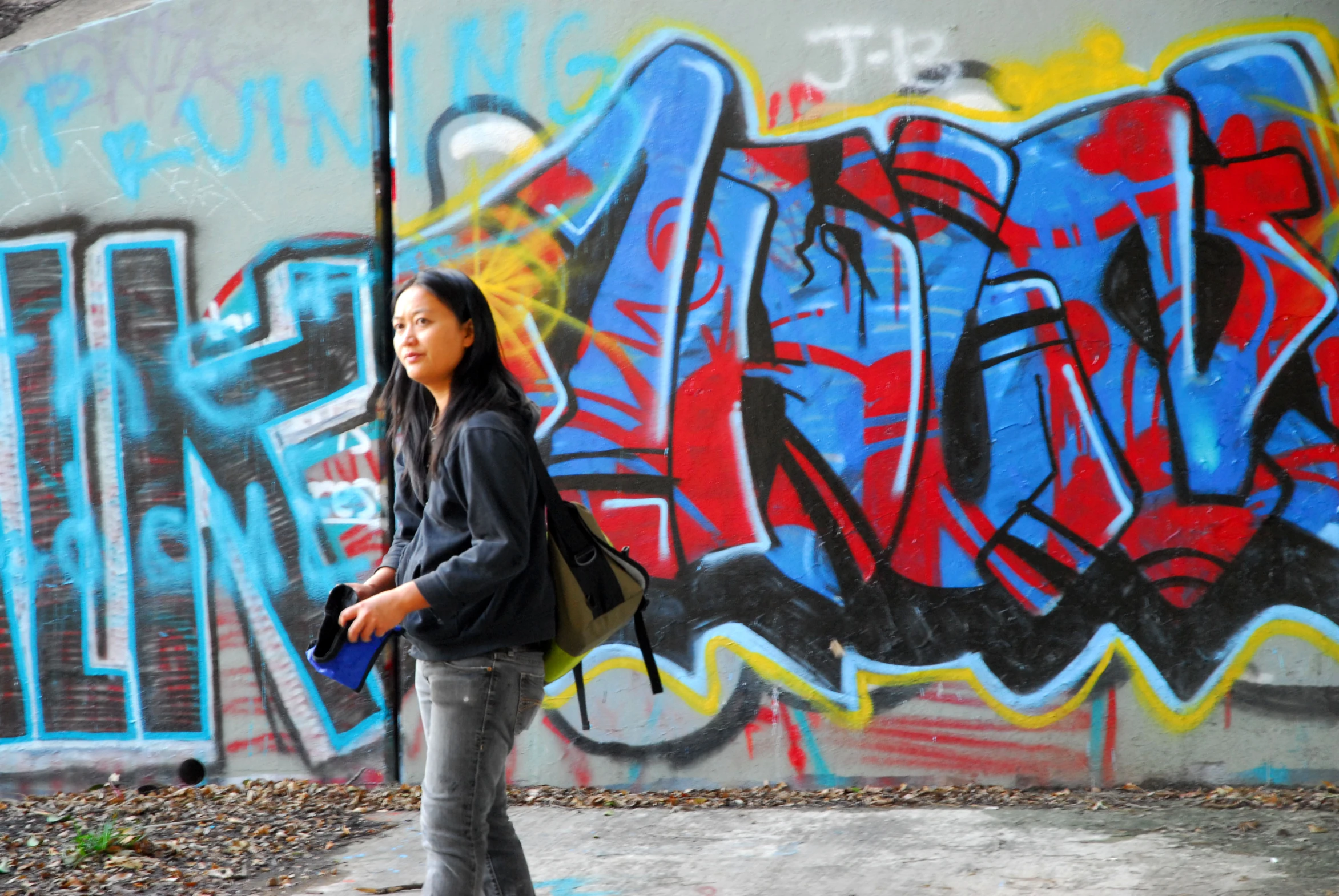 there is a woman standing near the graffiti wall