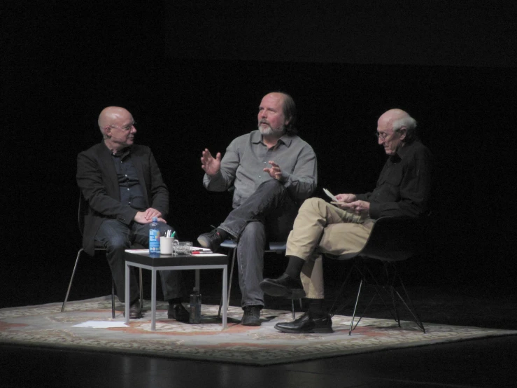 the group of men sit on stage talking