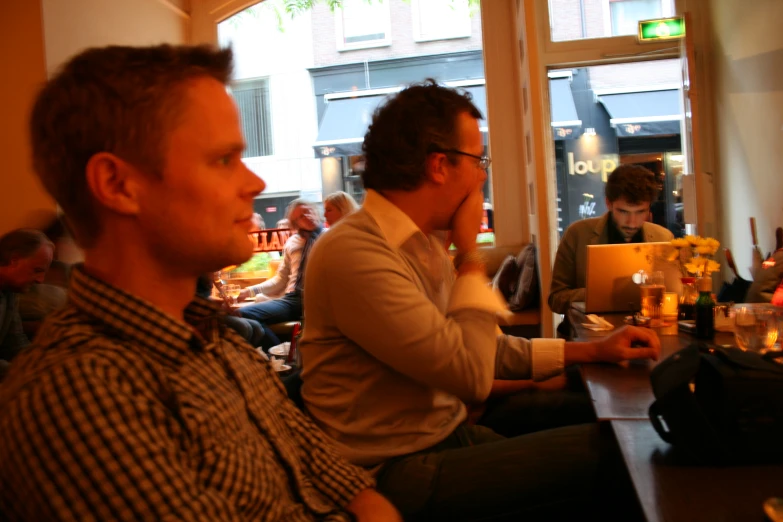 men sitting at tables looking away from the camera