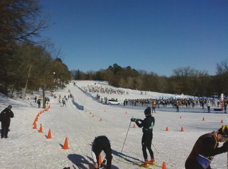 the people are skiing down a slope with orange cones