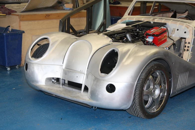 an old silver racing car with a large engine bay