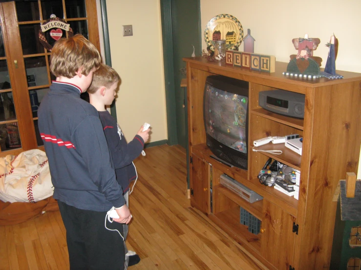 a couple of young men standing in front of a tv