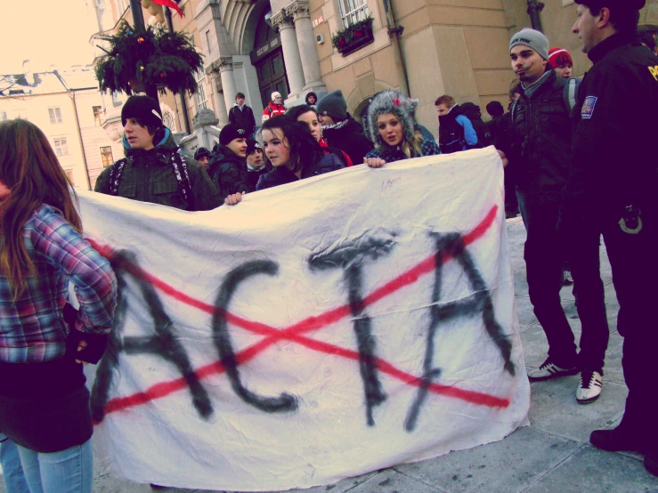 protesters at a protest hold a large sign that reads acia