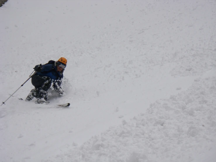 a man in orange hat on skis going down a hill