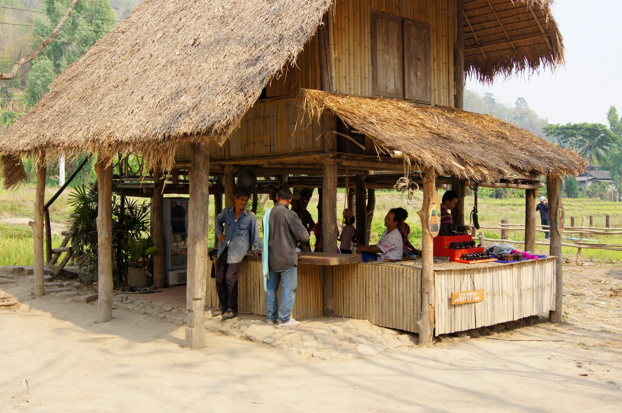 a group of people are standing outside of a hut