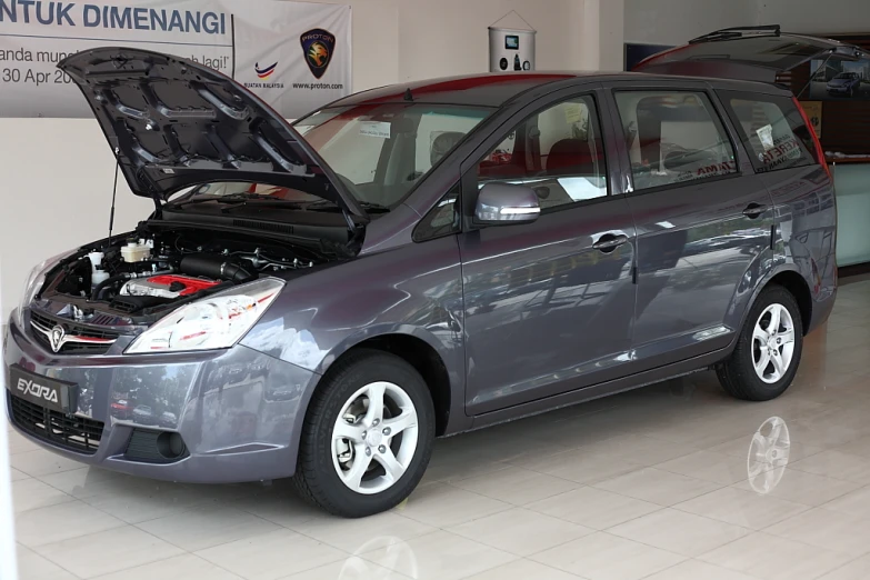 a gray car with an open hood sits in the showroom