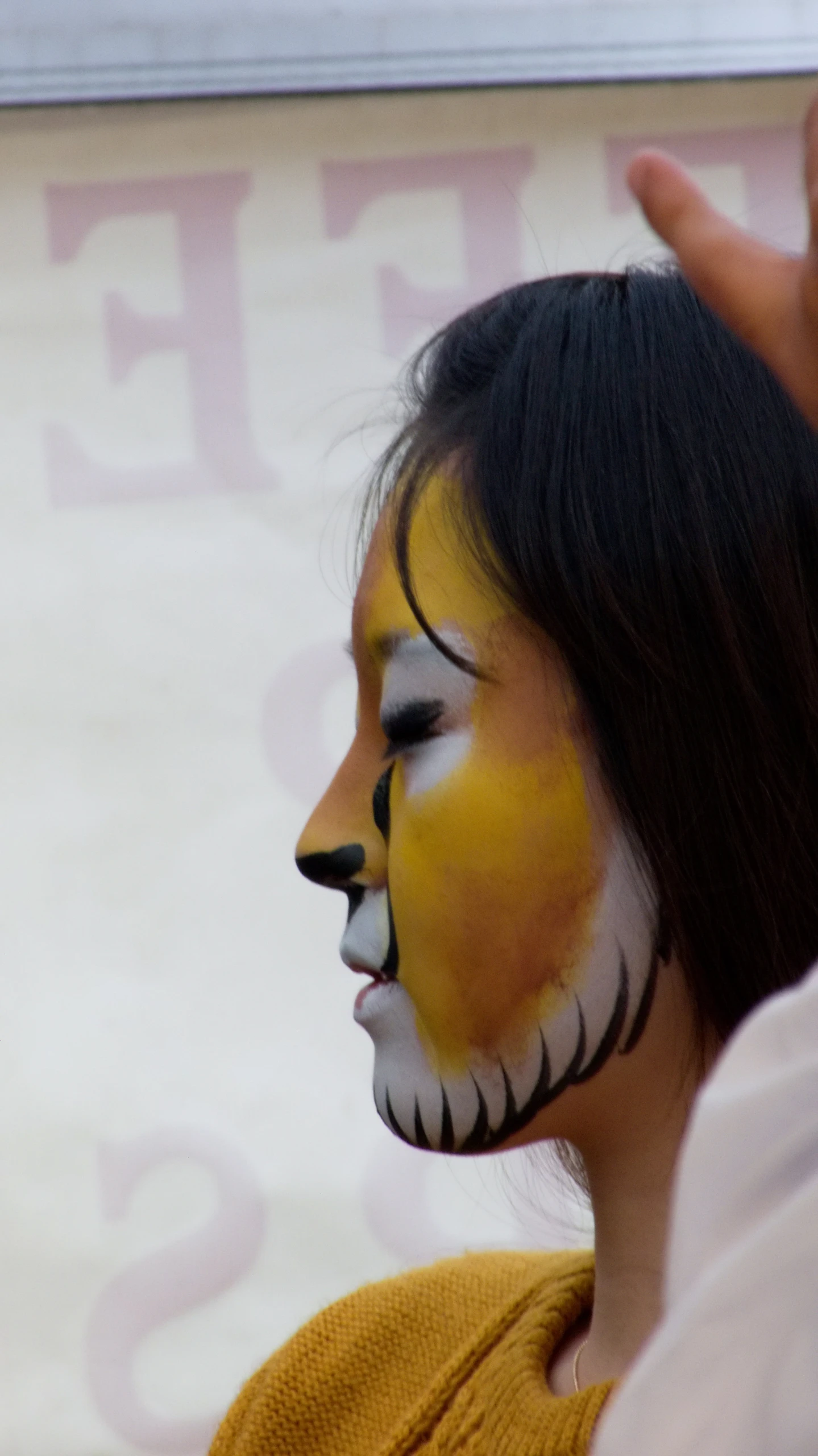 a woman with painted face and face paint holding her hand up to her nose