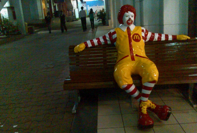 a large ronald mcdonald statue sitting on top of a bench