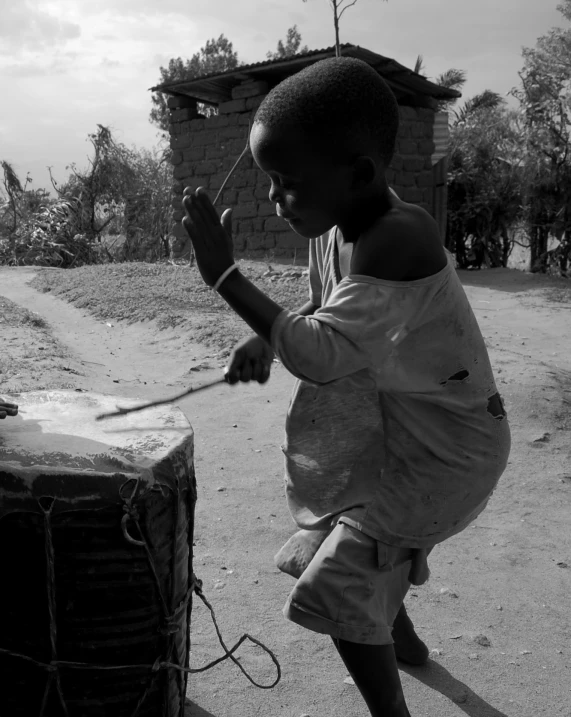  in an apron playing music while standing near a drum