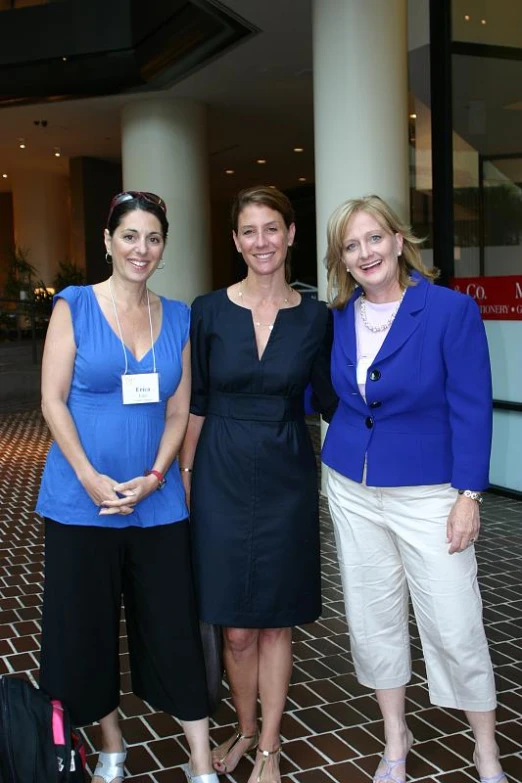 three women in formal wear smiling for a po