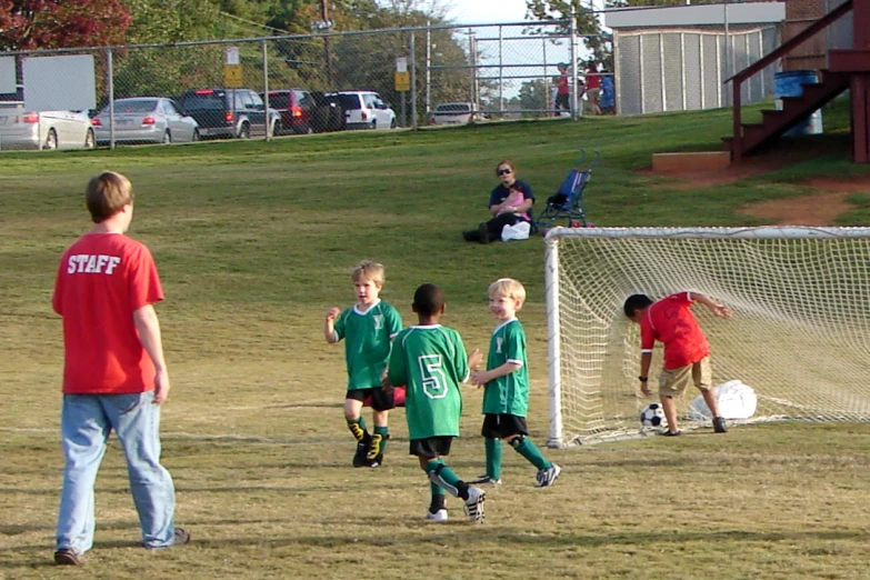 two teams of boys play soccer with parents and friends