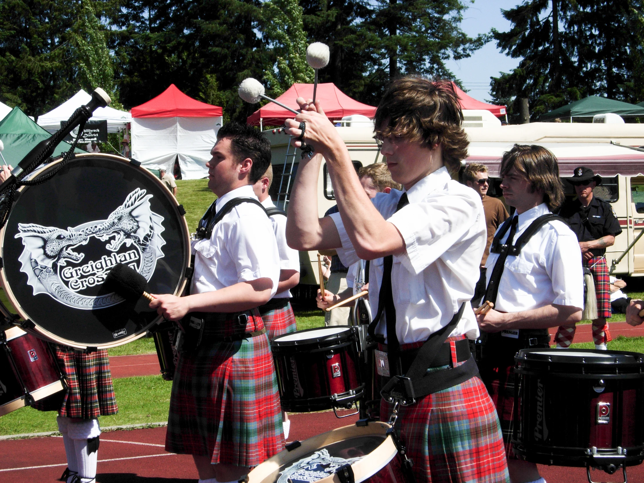 some men wearing kilts are holding drums