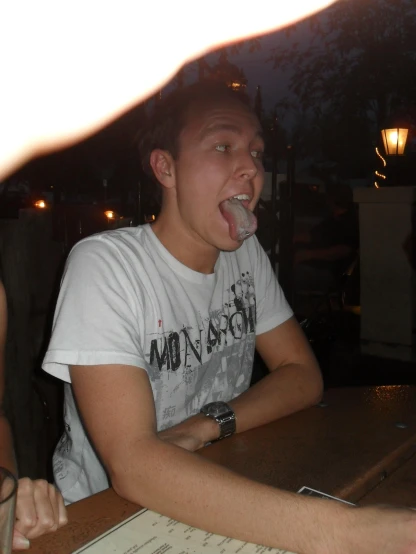 a man sticking his tongue out sitting at a table