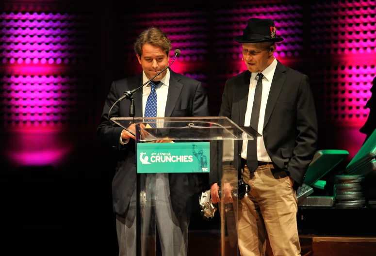 a couple of men are standing at a podium