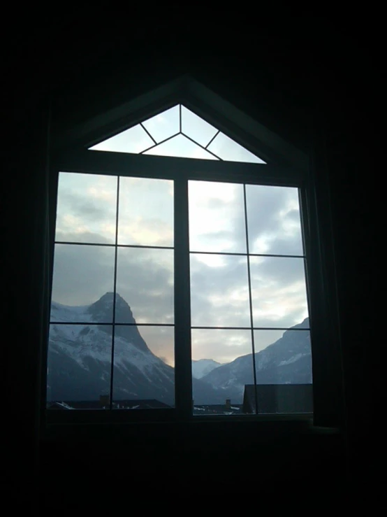 an open window with a view of snow covered mountains