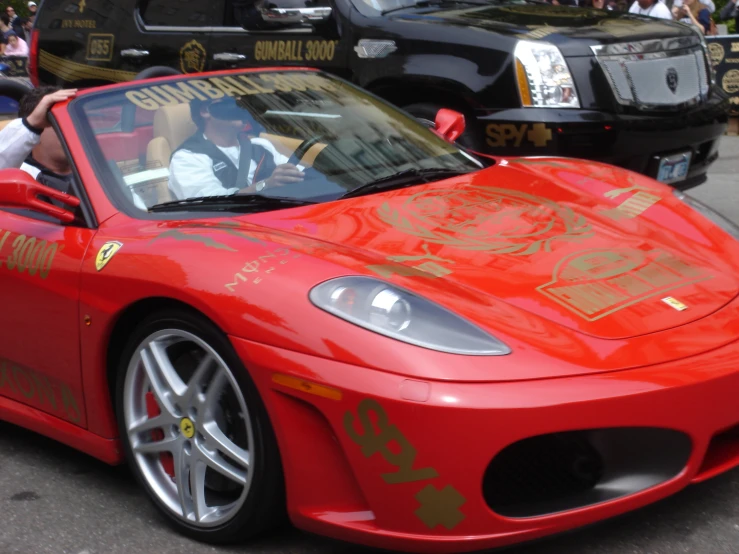 a woman that is sitting in the back of a red ferrari