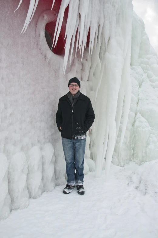 a person standing next to a waterfall of ice