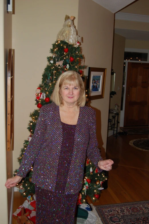 a woman in pajamas standing by a christmas tree