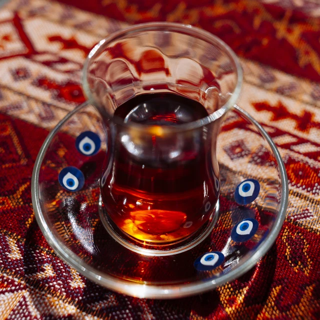 a s glass filled with liquid on top of a colorful table cloth