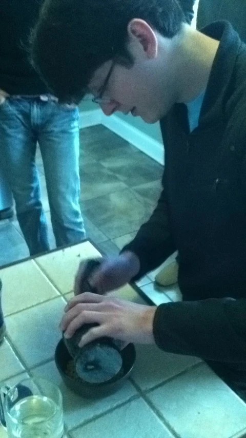 a man standing at a counter using a grinder