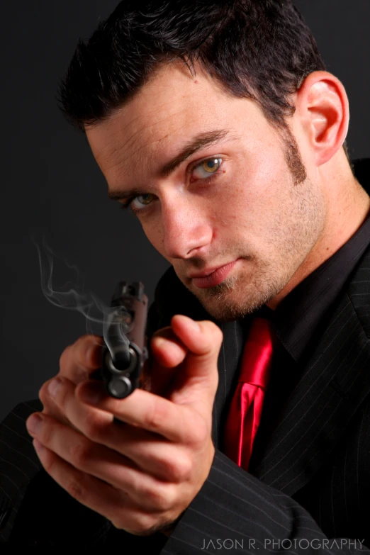 a man in a suit holding a small gun