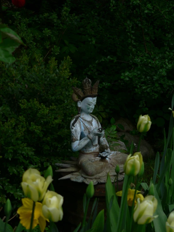 a statue is surrounded by tulips and greenery