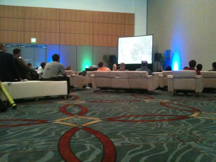 people sitting on sofas in front of a projection screen