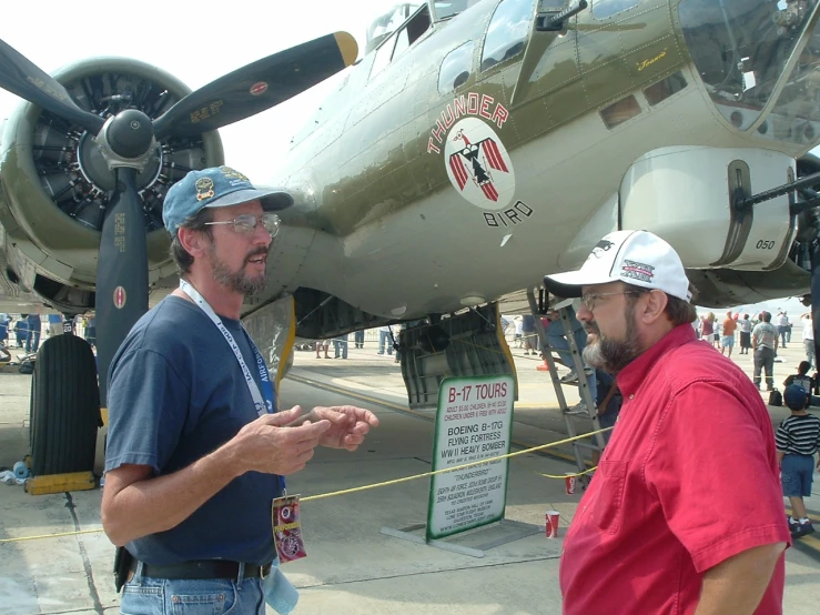 the two men are talking outside the large plane