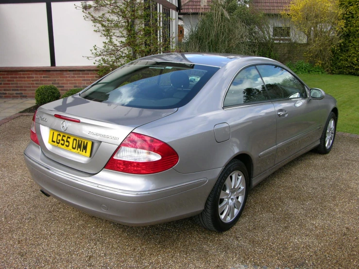 a grey mercedes cls is parked in front of a house