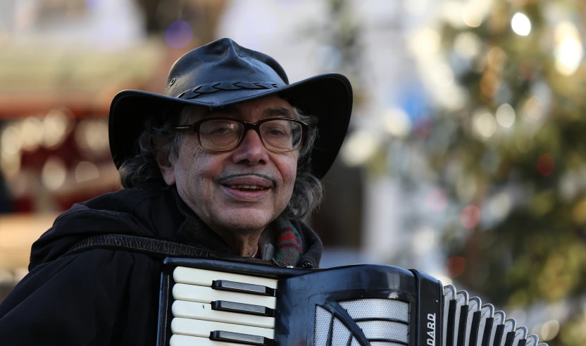 a man with glasses and a cowboy hat playing an accordion