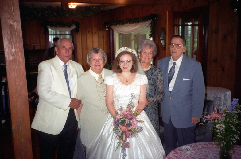 the bride and groom pose for a po with their grandmothers