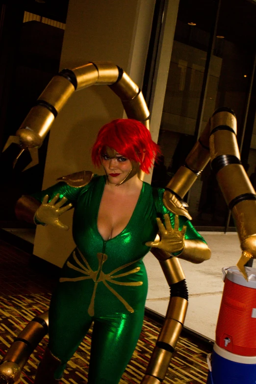 an unusual woman dressed as a sci - fidget stands with a large gold spider in front of her