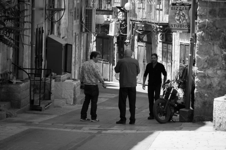 a man stands on the sidewalk with another man next to him and holds a motorcycle