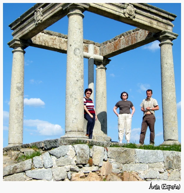 three people standing in front of the ruins of a building