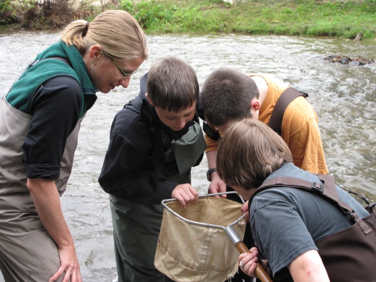 a group of young people standing next to each other while fishing on the river