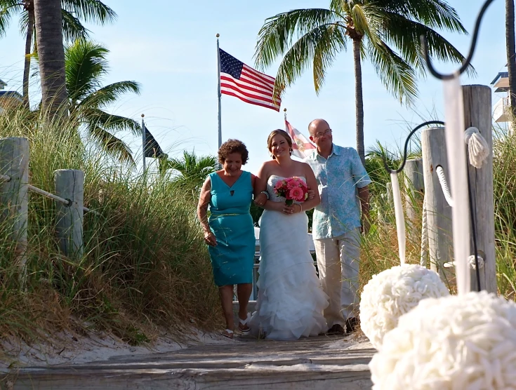 the bride and groom are walking down the beach walkway together