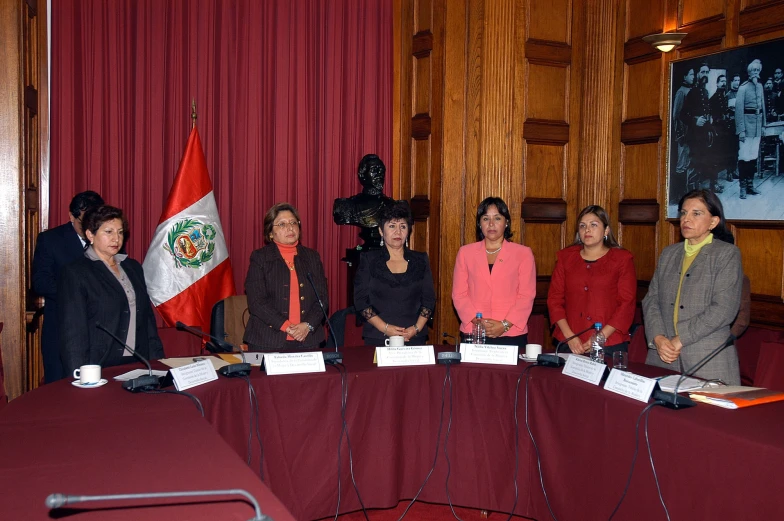 a group of people standing around a long table with two microphones