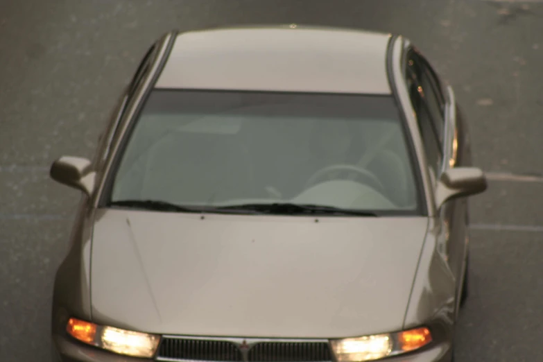 view from above at car with headlights on grey pavement