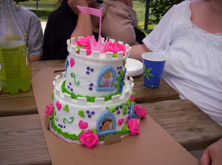 three people sitting and one woman holding a pink cup on the bench