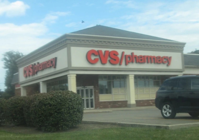 a car parked outside a cv's pharmacy store in the grass