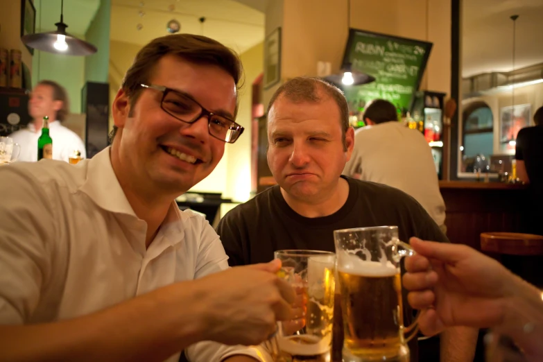 two men sitting at a bar having beers