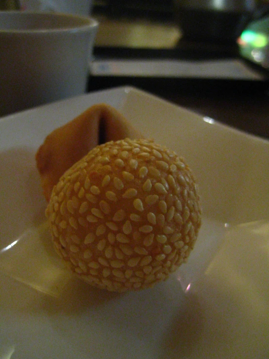 a small orange on a white plate next to a cup